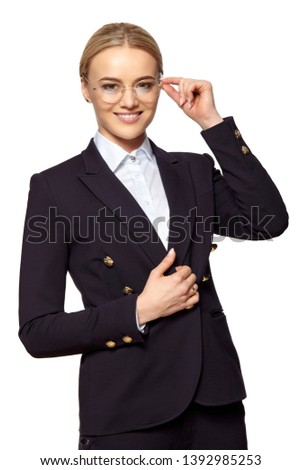Studio portrait of young happy smiling business woman in a gold eyeglasses and dark business suit.