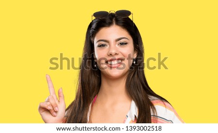 Teenager girl on summer vacation pointing with the index finger a great idea over isolated yellow background