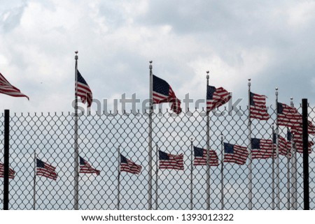 Waving usa flags behind metallic fence grid
