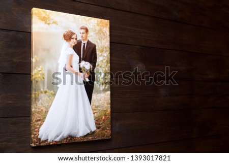 Photo canvas print. Sample of stretched wedding photography with gallery wrap, side view. Bridal portrait hanging on brown wooden wall