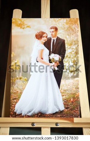 Photo canvas print stands on a wooden easel. Sample of stretched wedding photography with gallery wrapping on a stretcher bar