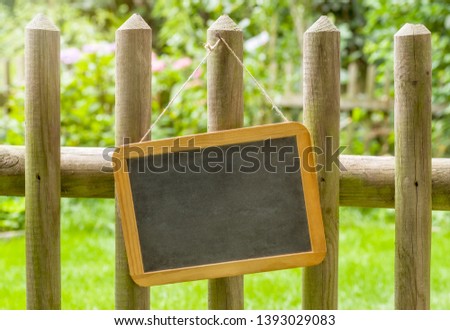 An empty blackboard on a wooden fence