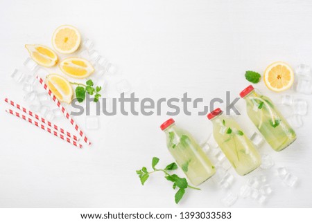 Fresh homemade summer  lemonade or mojito cocktail with lemon and mint. Cold refreshing drink or beverage with ice on white background, top view