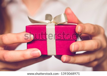 Female hands holding a small red box with a gift. Birthday concept