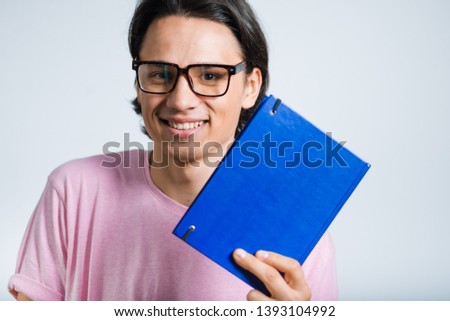 handsome young man with book, hipster, studio photo on gray background
