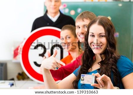 Driving school - driving instructor in his class and a female student driver looking in the Camera, in the background are traffic signs