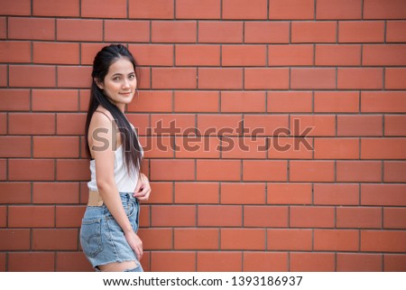 Portrait of beautiful asian chic girl pose for take a picture on brick wall background,Lifestyle of teen thailand people,Modern woman happy concept,Punk rock style