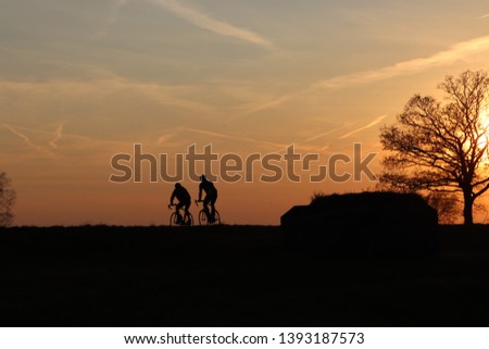 Cyclists silhouette at sunset; blue and orange sky