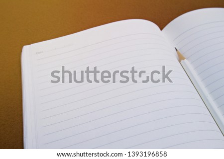 Sharpened pencil on black page placed on brown surface. This photo is suitable for adding texts and creating cards