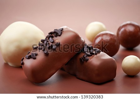 various chocolate candies on brown background