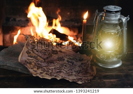 Pirate treasure map and kerosene lamp over a burning fire background. Treasure hunt concept.
