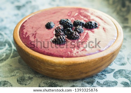 fruit smoothie with blackberries in a wooden cup on a blue tablecloth