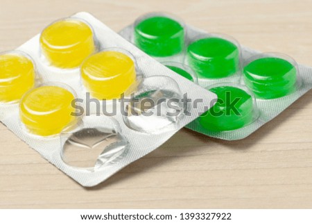 colored throat  lollipop pills at wooden table background. used pills pack.
