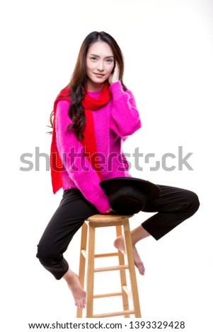 Charming young woman happy smiling. Sitting on a wooden chair.Wearing knitted pink sweater and red scarf.Fall and winter fashion concept.Isolated on white background.