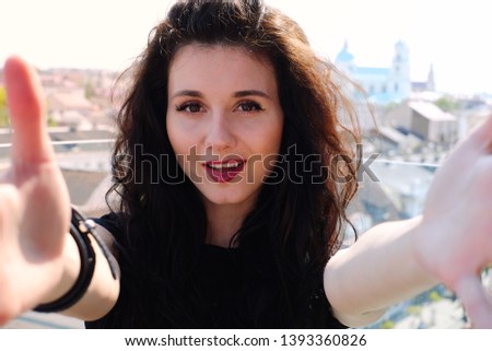 Happy young beautiful business woman doing a selfie photo on the camera. Girl travels in the city and takes a photo