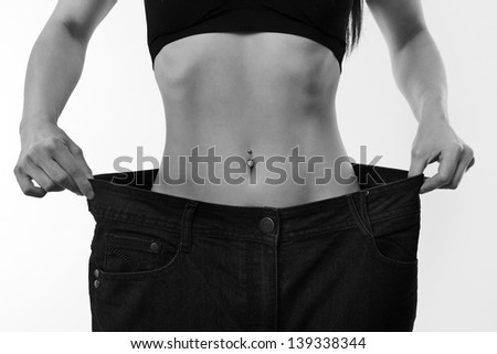A picture of a young slim woman in oversized pair of large blue jeans, Weight loss concept showing how much weight she lost after a diet