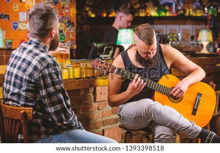 Friday relaxation in bar. Friends relaxing in bar or pub. Hipster brutal bearded spend leisure with friend in bar. Real men leisure. Cheerful friends relax with guitar music. Man play guitar in bar.