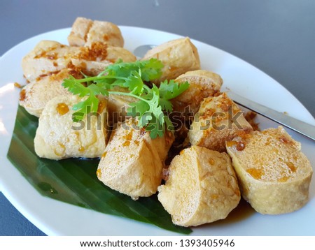 Asian food Tofu simmered in soy sauce with deep fried garlic and coriander. Traditional fried tofu on banana leaf.Asian food concept,soft focus,Select focus Royalty-Free Stock Photo #1393405946