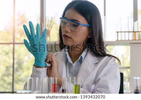 Scientist or practitioner young woman putting her hand with blue latex gloves while research in laboratory. 
