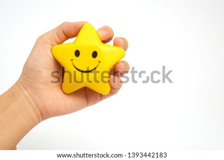 Hand holding or grabbing a smiling face star soft toy with writing space. 