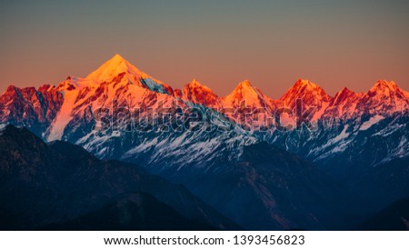 Panoramic view during sunset over snow cladded Panchchuli peaks falls in great Himalayan mountain range from Khalia top trekk trail at small hamlet Munsiyari, Kumaon region, Uttarakhand, India. Royalty-Free Stock Photo #1393456823