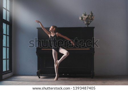 Cute little girl ballet dancer practicing in studio, old piano in background