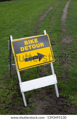 "Bike Detour" sign along a bicycle trail on a grass lawn, with space for text on top