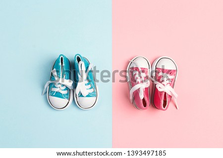 Pink baby girl and blue baby boy sneakers  on a pink and blue background. Flat lay, top view. Royalty-Free Stock Photo #1393497185
