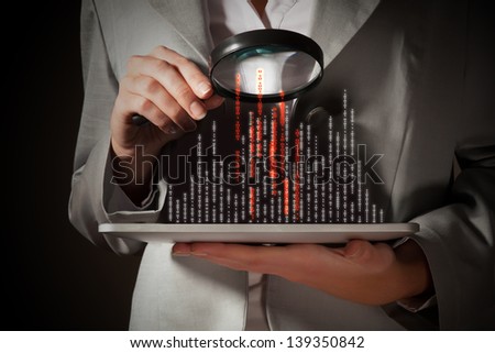 Businesswoman with magnifier glass examining binary code