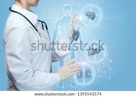 A medical worker adjusts a complex mechanism of health . A closeup of doctor operating with internal organs treatment mechanism of cogwheels with icons and models inside at digital human. Royalty-Free Stock Photo #1393543574