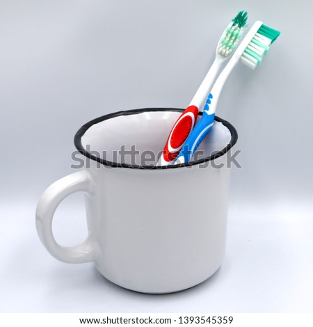 Isolated background image of blue and red toothbrush in white glass