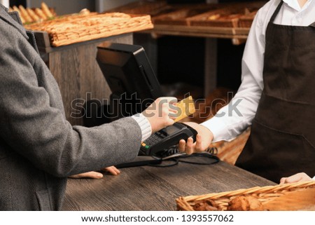 Woman with credit card using payment terminal at shop