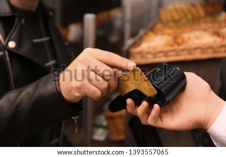 Man with credit card using payment terminal at shop, closeup
