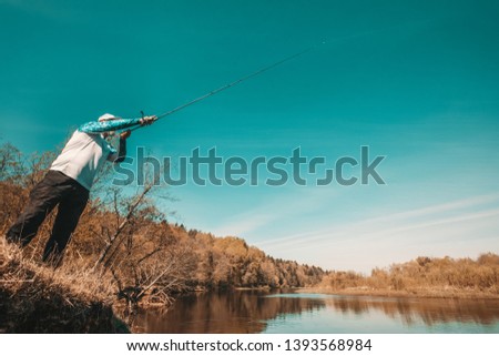 Fisherman with a spinning rod catching fish on a river 