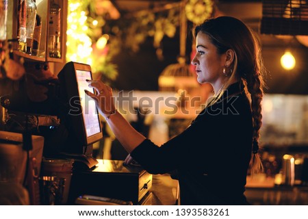 small business, people and service concept - A young waitress at counter in a small bar or restaurant Royalty-Free Stock Photo #1393583261