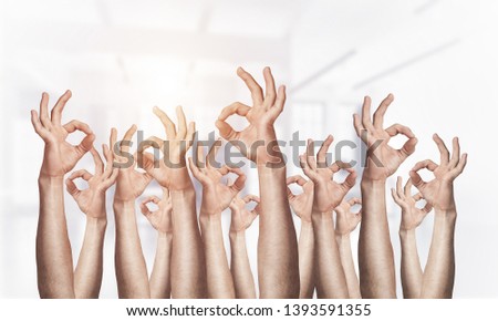 Row of man hands showing okay gesture. Agreement and approval group of signs. Human hands gesturing on light blurred background. Many arms raised together and present popular gesture.