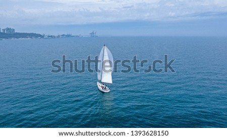 Bird's-eye view of a white sailing yacht against the background of the city and port