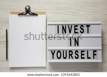 Modern board with 'You are your only limit' words, clipboard with blank sheet on a white wooden surface, top view. Copy space.