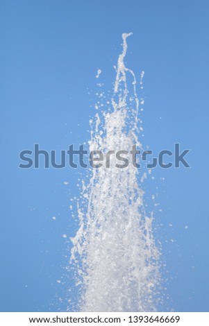 Spray of water fountain against the blue sky. Water splashes are out of focus.