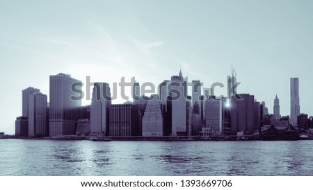 New York Financial District and the Lower Manhattan at dawn viewed from the Brooklyn Bridge Park. Blue black and white image.