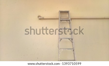 metal step ladder lean on yellow wall close up
