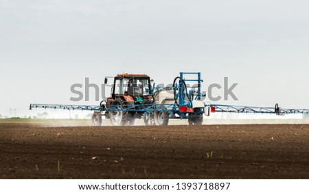Tractor spraying pesticides at  wheat fields