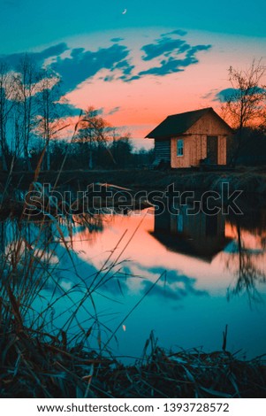 House at the lake reflected on water in sunset