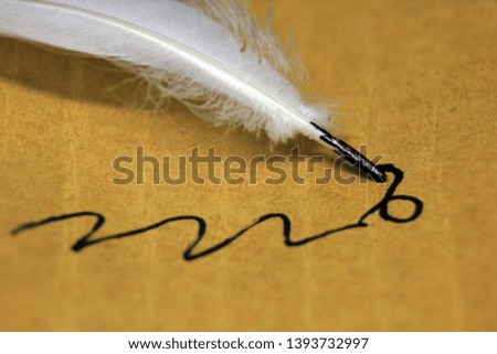 White Feather pen with black ink on brown paper ancient calligraphy.