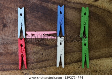 Colourful clothespins collection isolated on wooden background. It is Hi text.