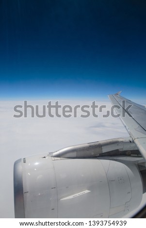 Flight over the clouds. Part of the wing of the plane under which sweep clouds