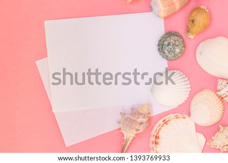 Empty white sheet of paper for text on a pink background. Background with shells and pebbles. Maritime theme.
