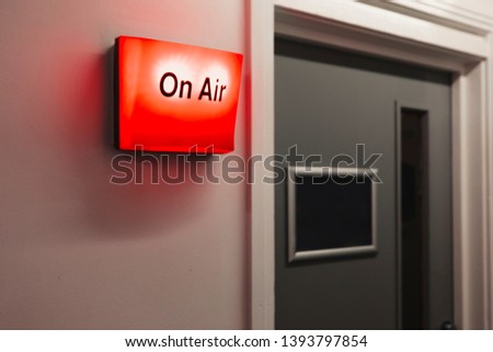 A close-up shot of a red on air sign on a wall in a recording studio, next to a doorway. Royalty-Free Stock Photo #1393797854