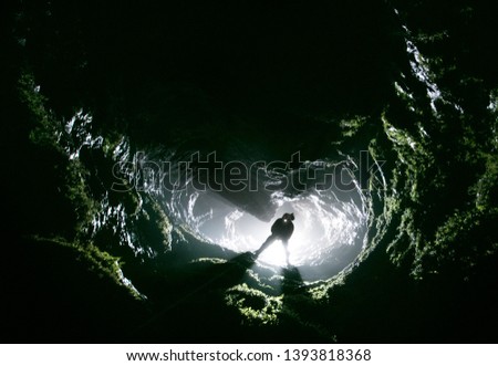 Silhouette of a caver climbing out of a cave Royalty-Free Stock Photo #1393818368