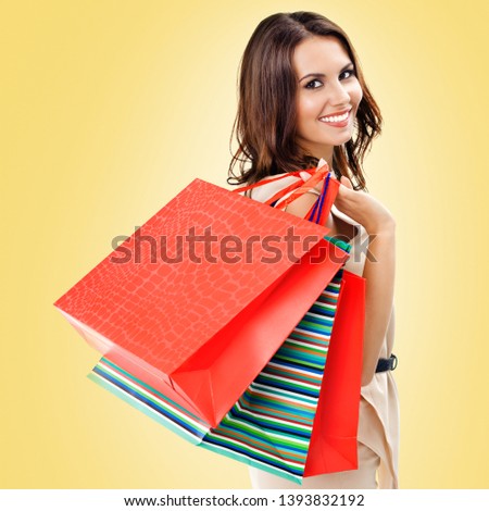 Shopping woman. Happy girl holding grocery bags, over yellow color background. Copyspace for some slogan, advertising or text. Square composition. Consumerism, sales and shopaholic concept picture. 
